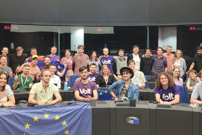 A large group of young Volt Violet membergs posing in the EU Parliament