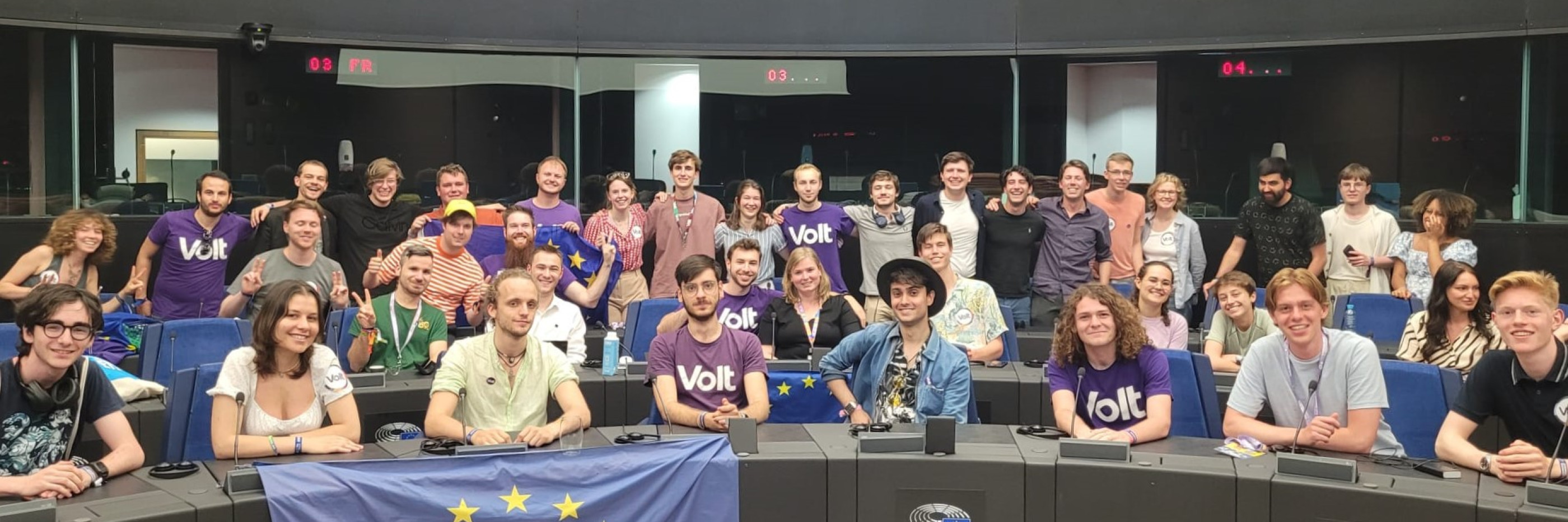 A large group of young Volt Violet membergs posing in the EU Parliament