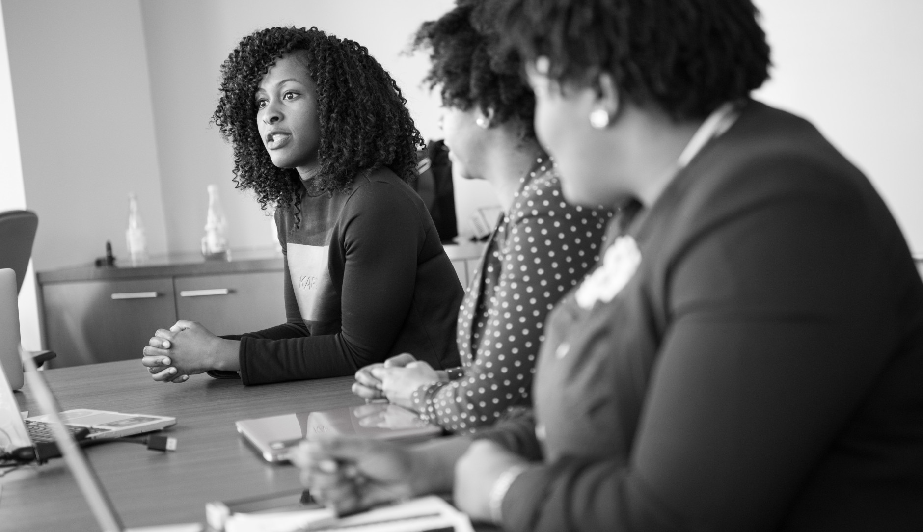 Three women sit at a boardroom table