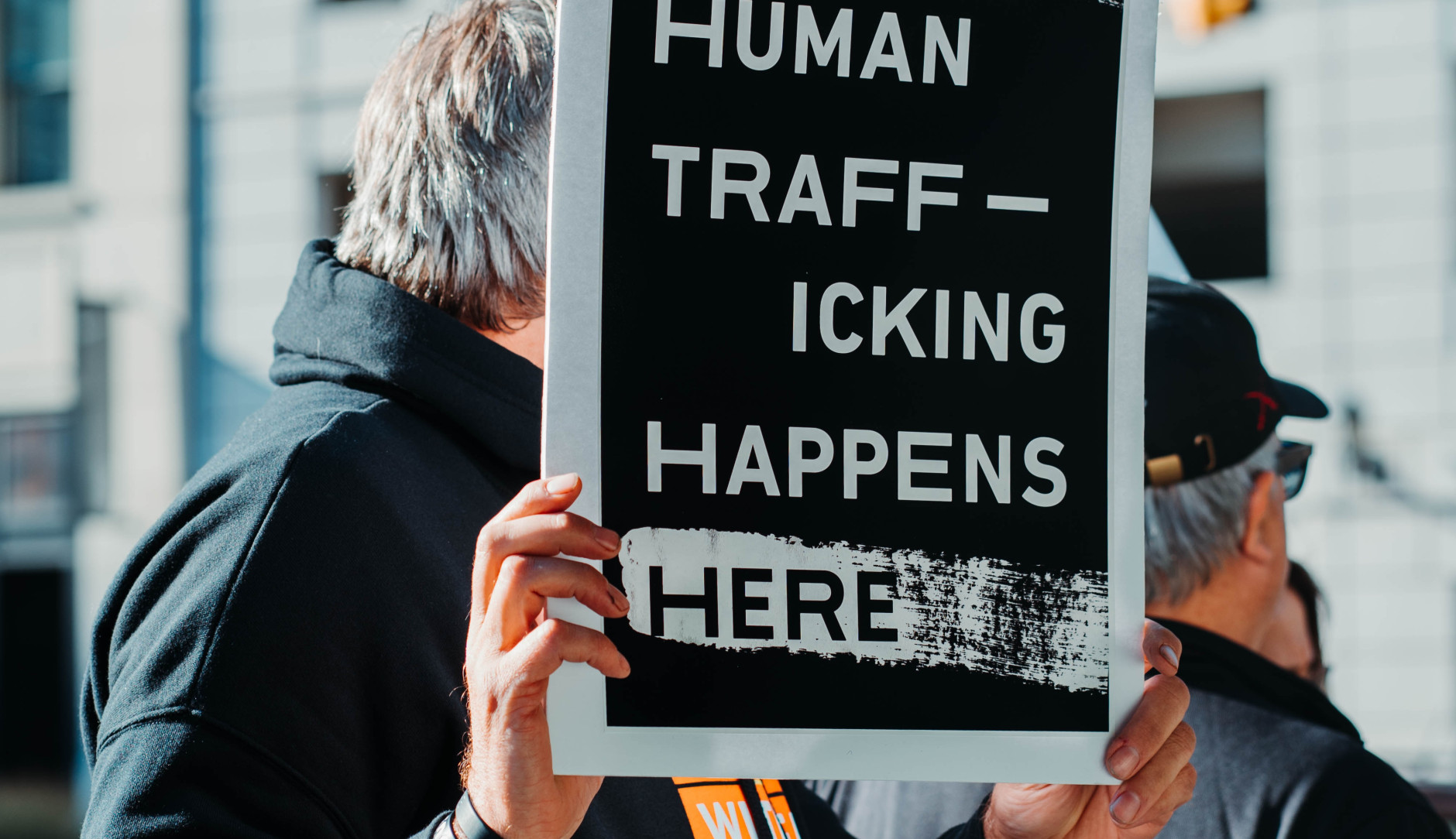 A man holding a sign that reads, 'Human Trafficking Happens Here'