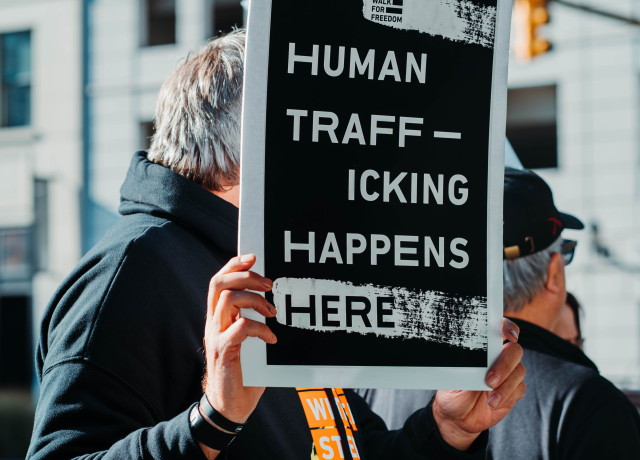 A man holding a sign that reads, 'Human Trafficking Happens Here'
