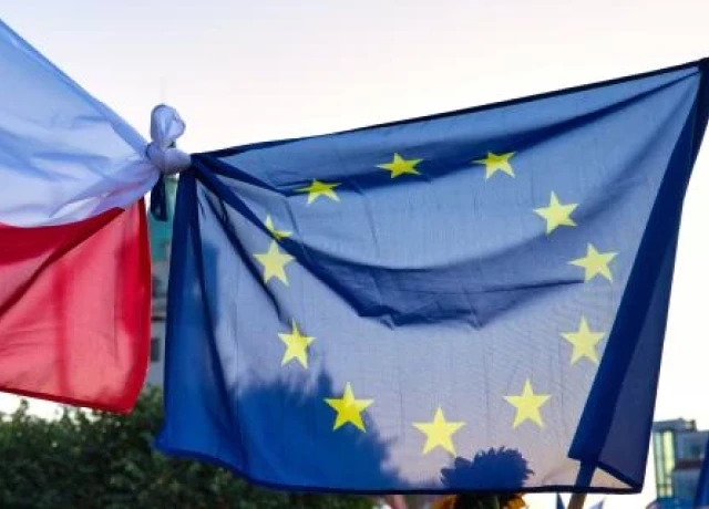 Polish and European Union flag tied together and raised in the air.