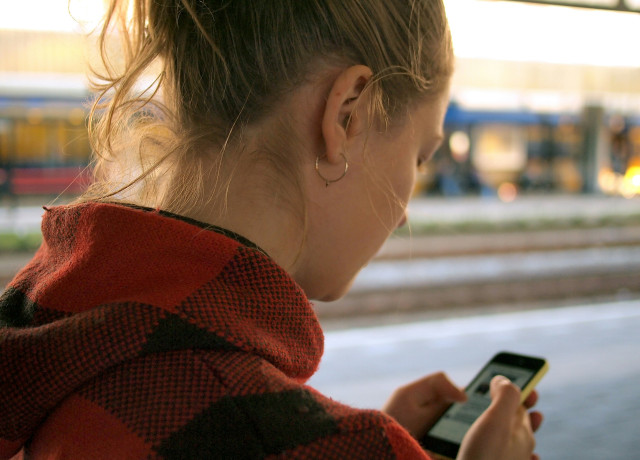 Young woman viewing screen and typing on mobile phone