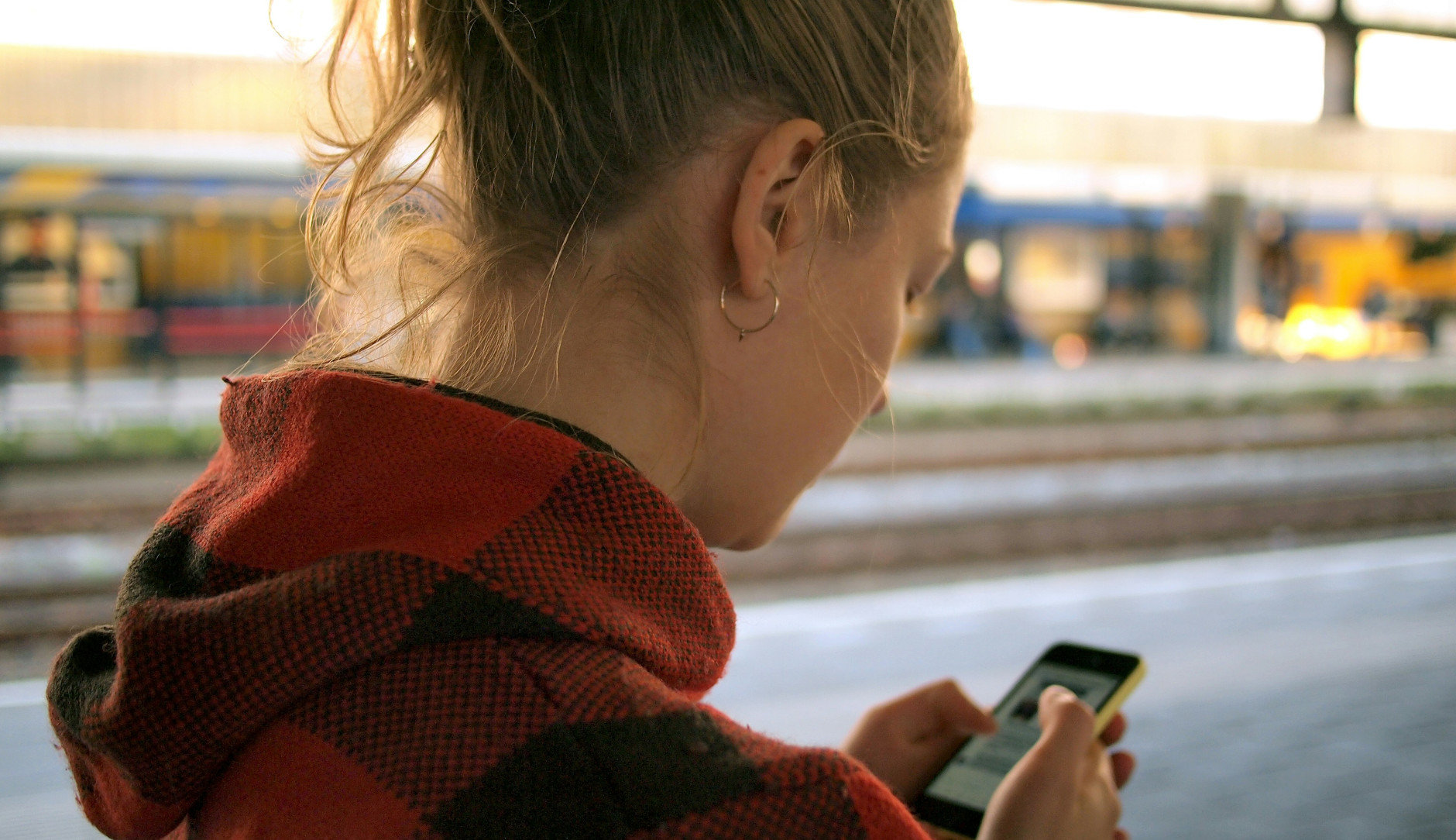 Young woman viewing screen and typing on mobile phone