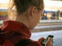 Young woman viewing screen and typing on mobile phone