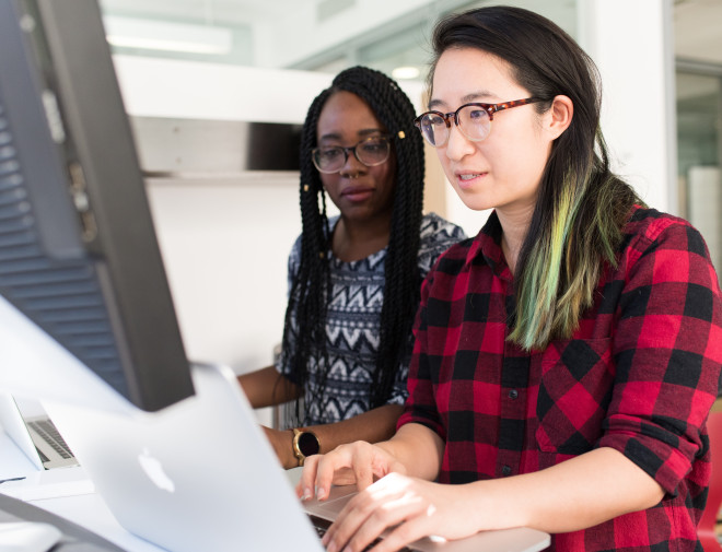 Two women of colour are working together on a laptop