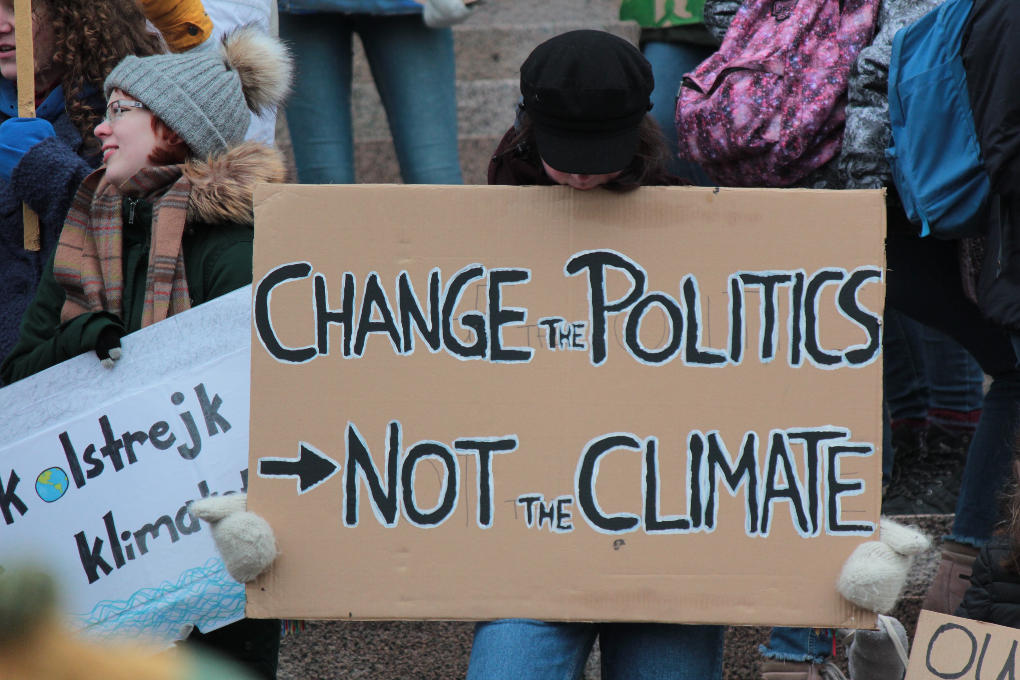 Person holds sign saying "Change the politics, not the climate"
